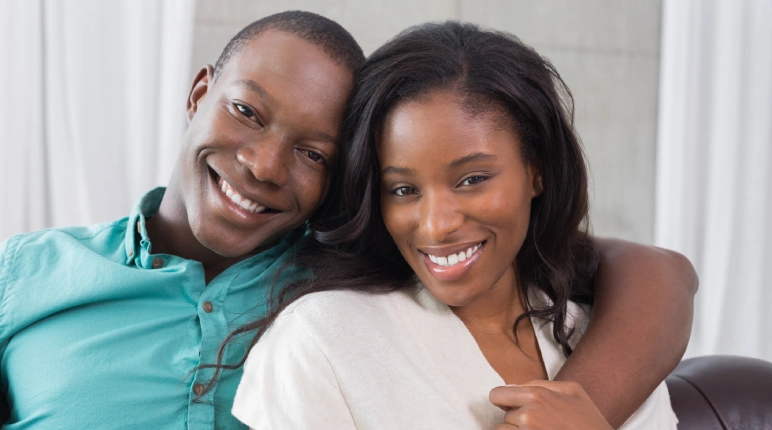 Smiling couple embracing on a couch.