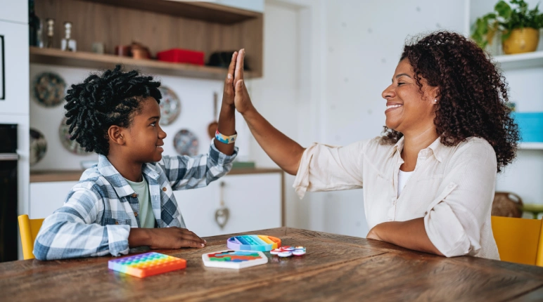 Mother and child high-five at table.