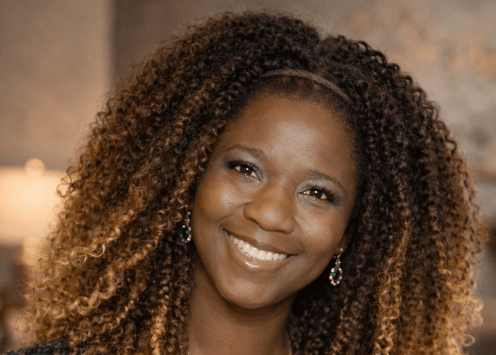 Smiling woman with curly hair, earrings.