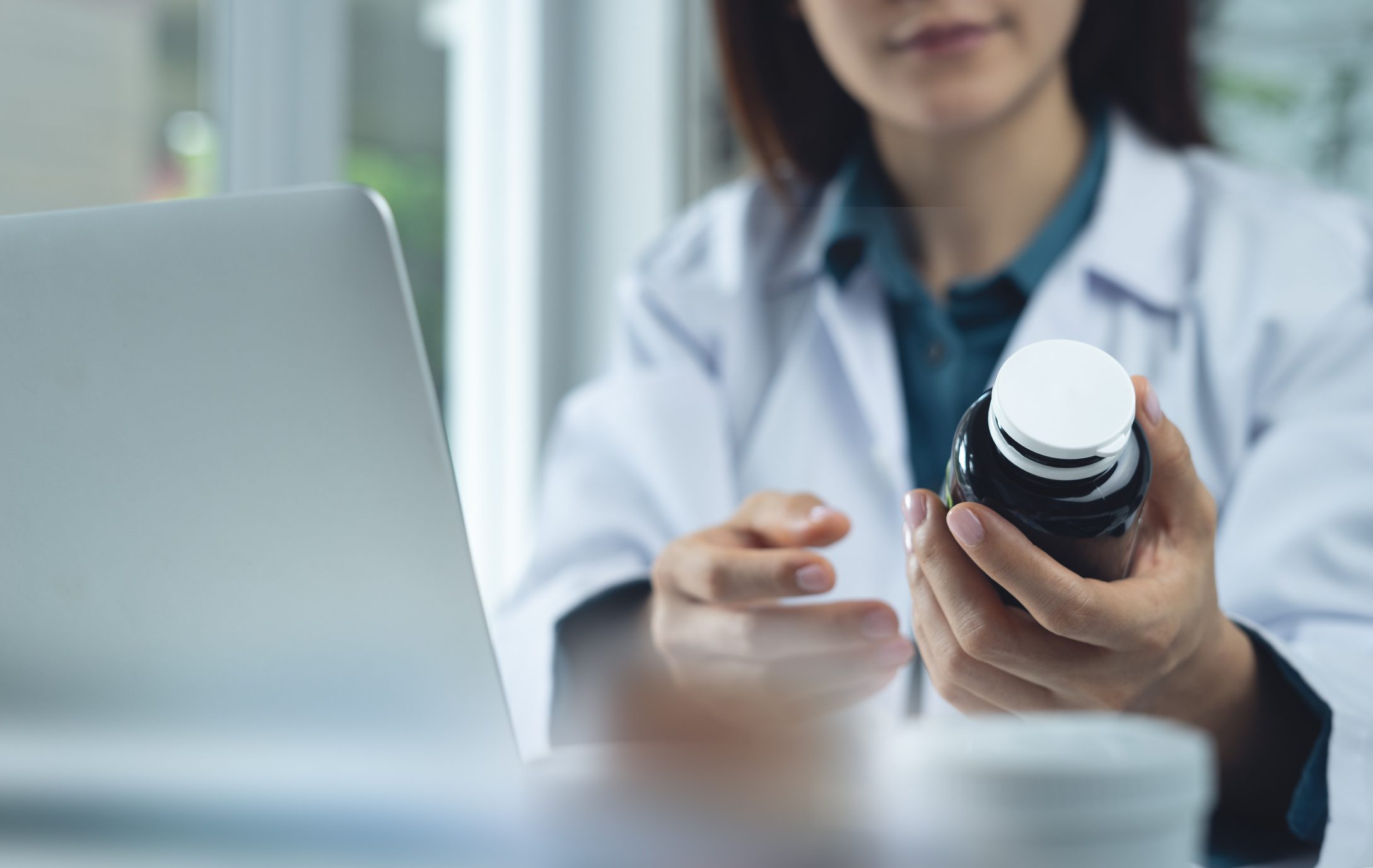 Closeup, medical doctor holding medicine bottle and checks for accuracy on the antibiotics and disinfectant list at medical clinic. Female pharmacist working at hospital