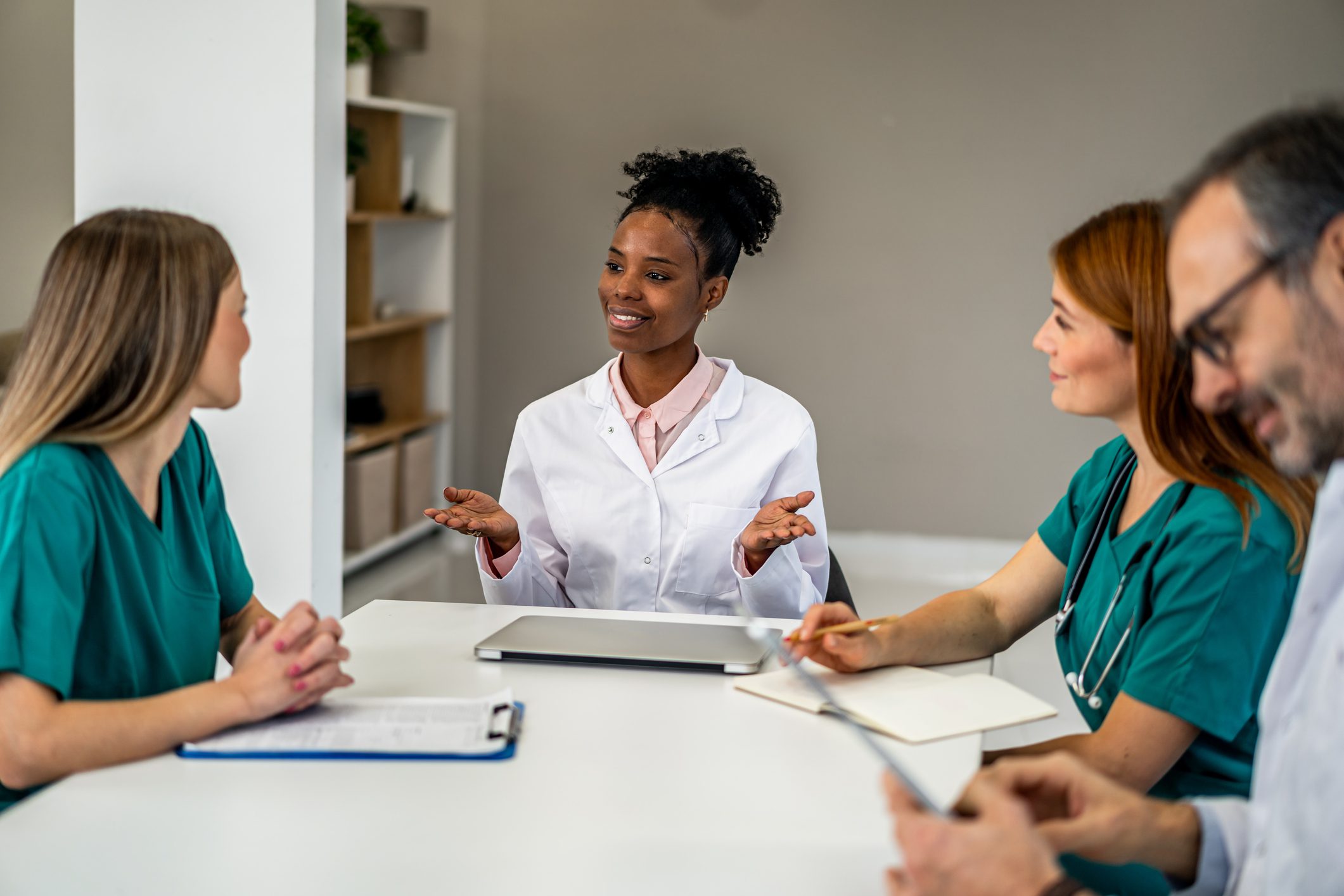 Diverse medical team members collaborating during a hospital conference. Black doctor leading discussion with nurses and colleagues