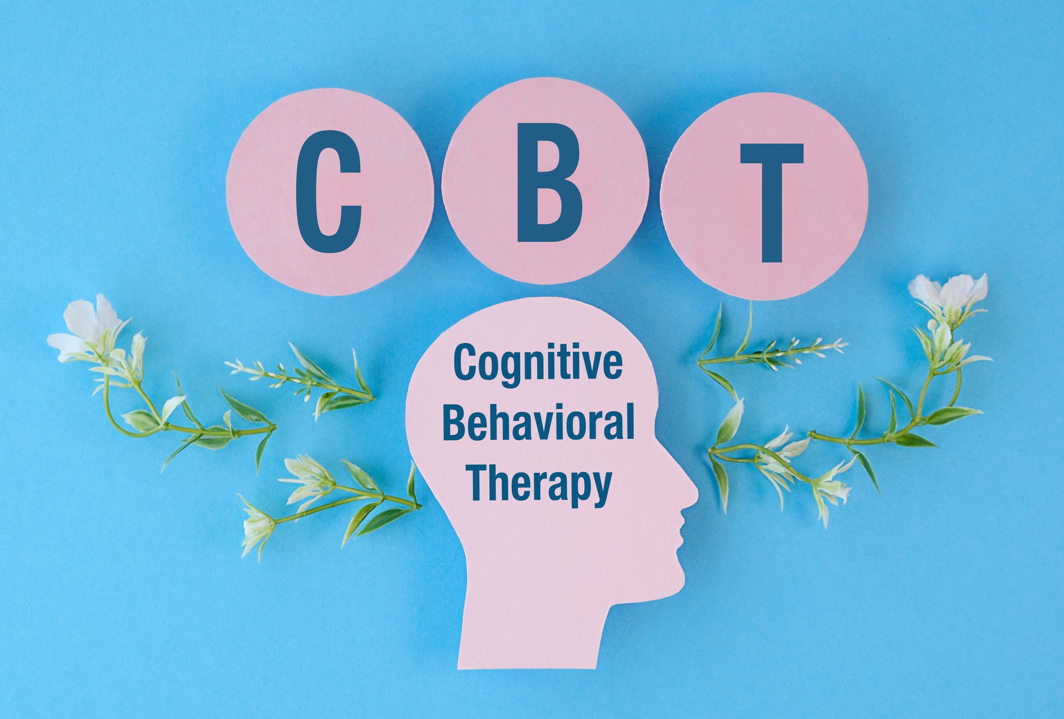 A head with the letters CBT written on it. The head is surrounded by flowers. The flowers are green and white